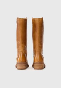 Bottes en cuir marron, montant jusqu'au genou, avec une texture lisse, des talons blocs rectangulaires et des coutures visibles à l'arrière.