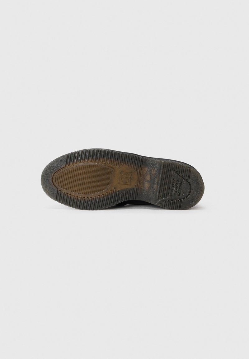 Black sneaker sole with textured rubber patterns, including grooves and a circular design. Features a small embossed logo near the heel.