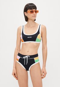 Czarny zestaw bikini z kroplą z białymi wykończeniami i kolorowymi bocznymi panelami w różowym, zielonym i pomarańczowym kolorze. Do dołu pasuje dopasowany wzór.