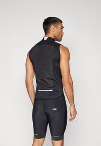 Maglia da ciclismo nera senza maniche con schiena in mesh, dettagli riflettenti e pantaloni da ciclismo neri aderenti con imbottitura. Texture liscia.