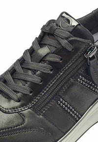 Black leather sneaker with textured surface, tonal laces, side zipper detail, and decorative metal studs on the outer side.