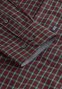 Camicia a maniche lunghe a quadri rossi e verdi, realizzata in tessuto dalla texture morbida, con fodera interna grigia e bottoni di plastica grigi.