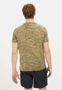 Koszulka z krótkim rękawem w wielokolorowym, teksturowanym materiale z wirującymi wzorami. Uzupełniona czarnymi szortami cargo. Zademonstrowana z tyłu.