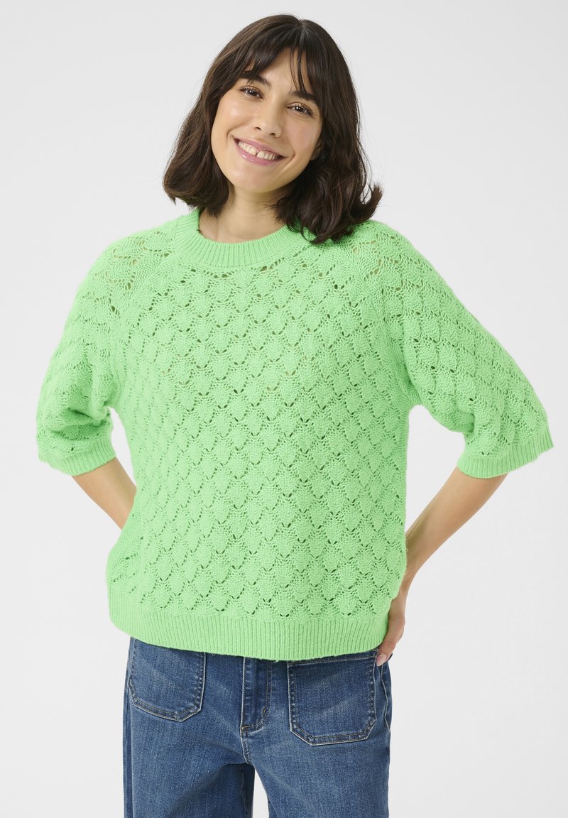 Mintgroene, lichte gebreide trui met een textuurpatroon in diamanten, ribbelkraag en korte mouwen, gecombineerd met denim jeans.