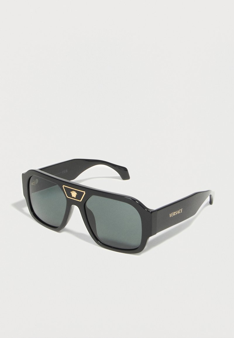 Μαύρα ορθογώνια γυαλιά ηλίου Versace με σκουρόχρωμους φακούς, χρυσό λογότυπο Medusa στη γέφυρα και κείμενο "Versace" στο πλάι του βραχίονα.