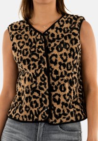 Gilet con stampa leopardata in un tessuto morbido e texturizzato, rifinito con dettagli neri e bottoni frontali. Presenta una vestibilità comoda e senza maniche.