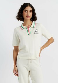 Polo-stijl top van crèmekleurige gebreide stof met korte mouwen, voorzien van een roze en groene gestreepte kraag en een geborduurd Snoopy-ontwerp.