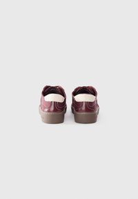 Burgundy leather shoes with a white accent, rounded back, and rubber sole. Features contrasting stitching and a textured cuff.