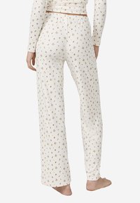 Pantalones largos y ligeros en color crema con un estampado floral en rosa y amarillo. Cuentan con una cinturilla elástica y un corte relajado.