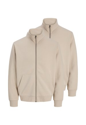 To beige lynlåstrøjer med ståkraver, forlommer og ribbede ærmeafslutninger og kanter, vist på en hvid baggrund.