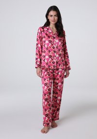 Set di pigiama floreale con sfondo rosa e fiori scuri e chiari, realizzato in tessuto morbido, con camicia a bottone e pantaloni lunghi.