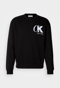 Sweat-shirt noir à col rond avec le logo blanc "CK Calvin Klein EST. 1968" sur le haut gauche de la poitrine, manches longues, et bords-côtes aux poignets et à l'ourlet.