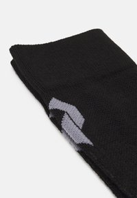 Calcetines de punto negros con un patrón geométrico gris. Textura suave con un borde superior ligeramente acanalado. Diseño compacto para versatilidad.