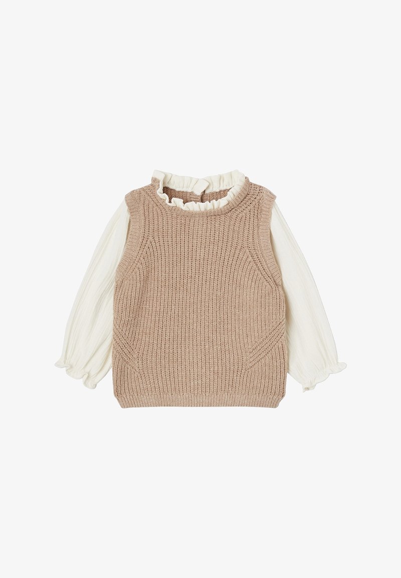 Gilet sans manches beige en tricot superposé sur un chemisier blanc à manches longues avec col et poignets à volants, présenté à plat sur fond blanc.