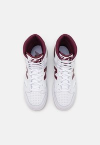 Pair of white high-top sneakers with burgundy inner lining and "N" logos, viewed from above on a plain white background.
