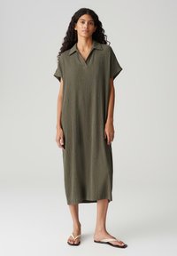 Olive green, knee-length dress with a relaxed fit, short sleeves, and a collared neckline made of textured fabric.