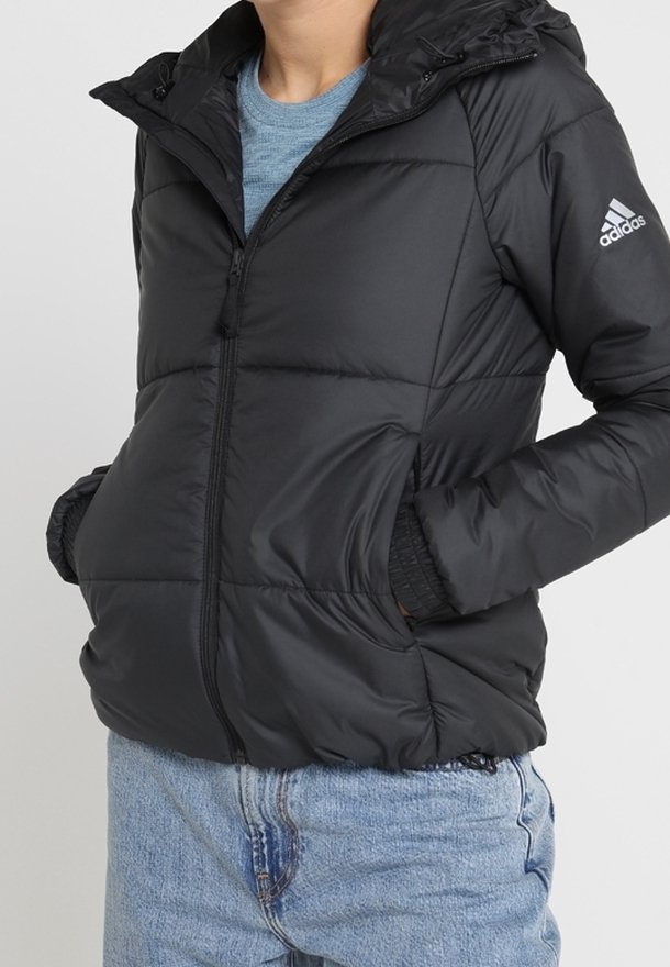 Sort pufferjakke med hætte, der har en frontlynlås, elastiske manchetter og et lille logo på højre ærme. Dennes iført over en blå skjorte.