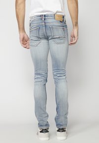 Světle modré skinny džíny z denimu, s zadními kapsami s kontrastním švem a značkovou etiketou na pásku.