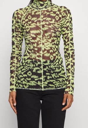 Haut à col roulé ajusté à manches longues avec imprimé animal abstrait vert néon et noir, porté avec un pantalon noir.