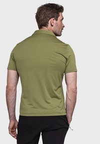 Kurzarm-Poloshirt in olivgrün mit strukturiertem Finish und geripptem Kragen, von hinten betrachtet, kombiniert mit schwarzen Hosen.