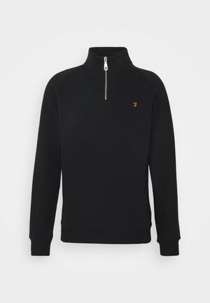 Zwarte pullover trui met een kwart rits, ribbels aan de mouwen en een klein geel logo op de linkerkant van de borst. Gemaakt van zacht textielmateriaal.