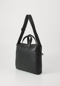 Black leather tote bag with dual top handles and an adjustable shoulder strap. Smooth texture, minimalist design, and subtle hardware accents.