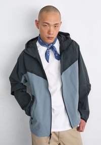 Lightweight zip-up jacket with a hood, featuring a blue and dark gray color block design. Smooth texture, elastic wrists, and adjustable hem.