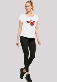 Camiseta blanca de manga corta con un estampado de cangrejo de dibujos animados en rojo, combinada con leggings negros y zapatillas deportivas negras. Un look casual simple.