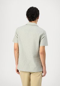 Korte mouwen gekraagde shirt in een lichtgrijze, gestructureerde stof. Heeft een rechte rugzoom en een eenvoudig ontwerp zonder zichtbare patronen.