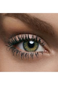 Lähi-kuva vihreästä silmästä, jossa on hyvin määritellyt mustat ripset, vaaleanruskeat silmäluomet ja hienovarainen hohto silmän ympärillä olevalla iholla.