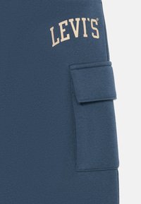 Sweatshirt azul-marinho da Levi's com tecido texturizado, apresentando um bolso frontal e texto do logótipo em creme em arco sobre o peito.