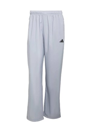 Jasnoszare spodnie sportowe z elastycznym paskiem w talii, prostym krojem nogawek oraz czarnym logo Adidas blisko lewej strony biodra. Gładka faktura.