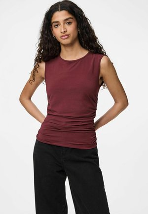 Top sin mangas de color burdeos hecho de una tela elástica, con lados fruncidos y escote redondo. Combinado con pantalones de pierna ancha negros.