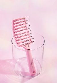 Culotte rose avec un design large et plat et des poils en métal, reposant dans un verre transparent. Le manche a un trou pour un accrochage facile.