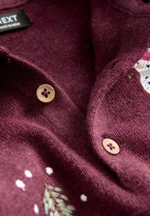 Burgunderfarbener Strickcardigan mit strukturiertem Finish, einem Schalkragen und beigen Knöpfen. Enthält gestickte Akzente von Bäumen und Schneeflocken.