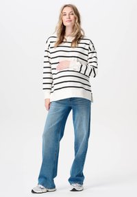 Svart- och vitrandig långärmad topp i kombination med ljusblå vida jeans. Outfiten har en avslappnad passform och är tillverkad av mjukt bomullsmaterial.