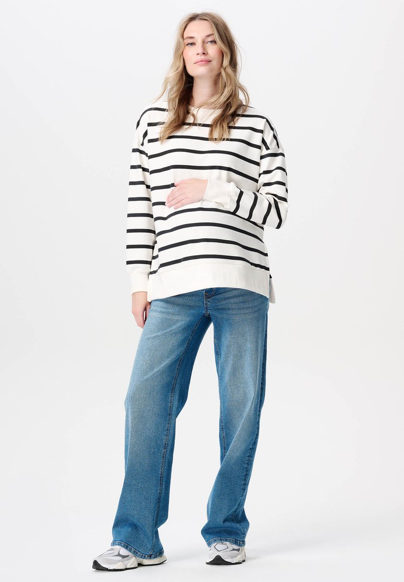Svart- och vitrandig långärmad topp i kombination med ljusblå vida jeans. Outfiten har en avslappnad passform och är tillverkad av mjukt bomullsmaterial.