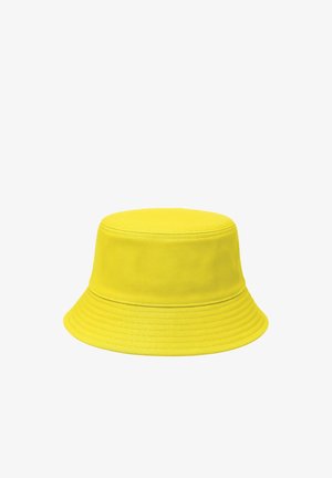 Jasnożółty bawełniany kapelusz typu bucket z przeszywanym rondem, pokazany na białym tle.