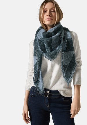 Grande sciarpa triangolare in verde scuro e blu, con un motivo a scacchi e bordi frangiati, indossata sopra un maglione grigio chiaro.