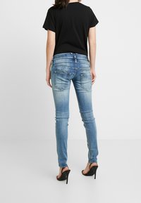 Blå denim skinny jeans med en bleknad tvätt, bakfickor med diskret sömnad, kombinerat med en svart t-shirt med kort ärm och högklackade skor.