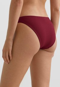 Bordo spodnji del bikini kopalk z teksturirano tkanino, srednje visokim pasom in minimalnim pokrivanjem. Brezšivni robovi izboljšajo udobje in prileganje.