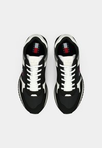 Black and white athletic shoes with a textured upper, lace closure, and logo accents on the sides, featuring a cushioned sole design.