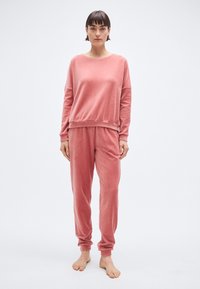 Ensemble de détente côtelé rose en tissu doux ; comprend un haut à manches longues à coupe décontractée et un pantalon fuselé avec poignets et taille élastiques.