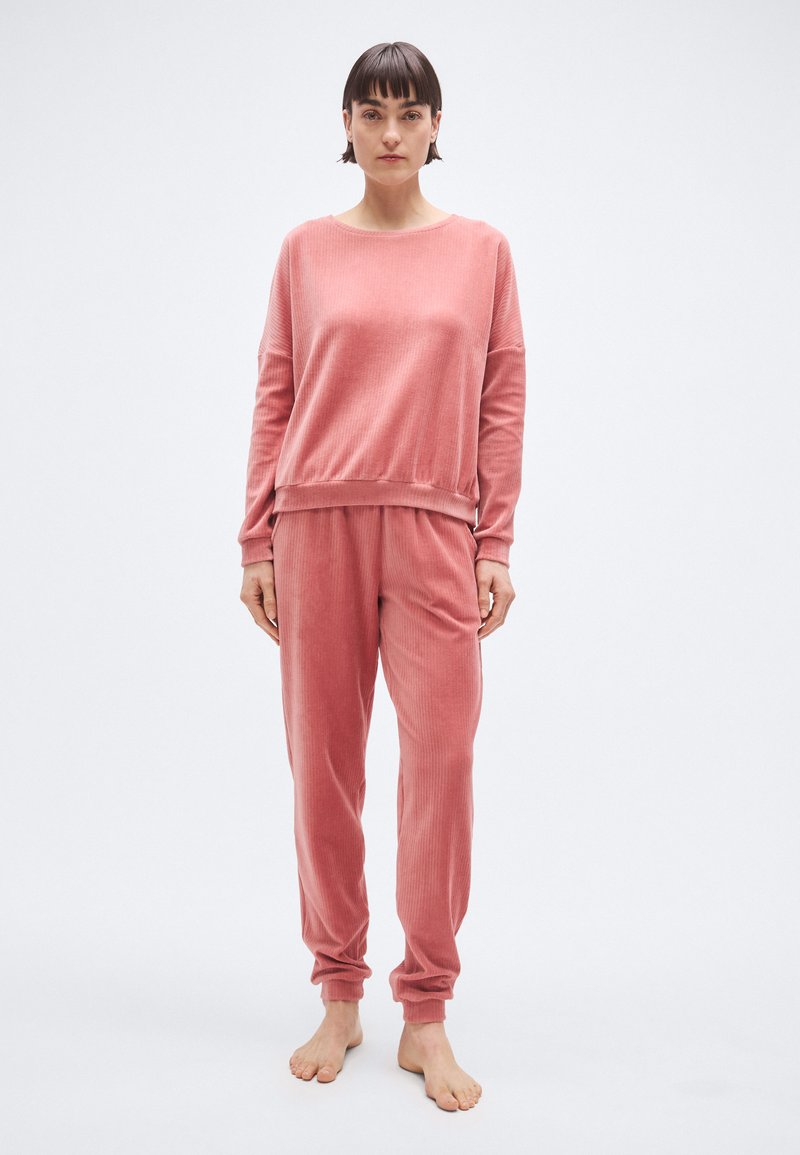 Ensemble de détente côtelé rose en tissu doux ; comprend un haut à manches longues à coupe décontractée et un pantalon fuselé avec poignets et taille élastiques.