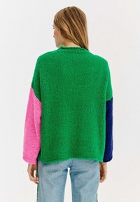 Bunter, übergroßer Pullover mit grünen, pinken und dunkelblauen Bereichen, aus grob gestricktem Stoff mit entspannter Passform und strukturiertem Finish.