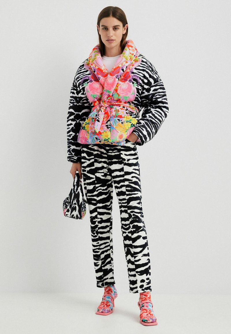 Kurtka puchowa z różowym kwiatowym wzorem i czarno-białym wzorem zebry. Dopasowane spodnie w wzór zebry i kolorowe buty w desenie. Kompaktowa torebka.