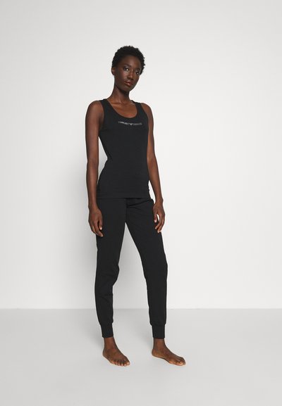Conjunto de top de tanque negro y joggers en tejido suave. El top tiene un escote redondo y detalle de logo, los joggers cuentan con puños elásticos y un ajuste relajado.
