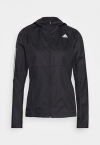 Schwarze winddichte Jacke mit Reißverschluss und Kapuze, ausgestattet mit einem weißen Adidas-Logo auf der Brust und reflektierenden Akzenten an den Ärmeln.