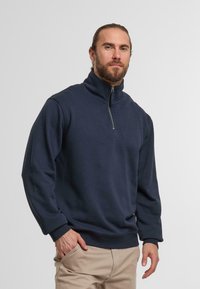 Granatowy sweatshirt z zamkiem na szyi, wykonany z miękkiego materiału, z luźnym krojem, ściągaczami na rękawach i płaskim dołem. Minimalistyczny design bez wzorów.