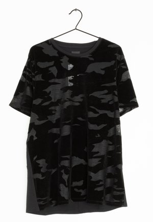 Zwart T-shirt met korte mouwen en donkergrijze camouflageprint, hangend aan een zwarte metalen hanger tegen een witte achtergrond.